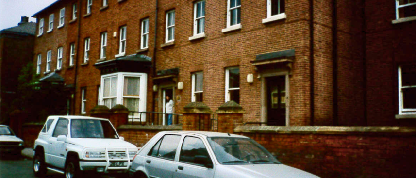 Brick building with old cars infront